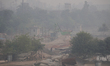A worker walks past a construction site enveloped in a thick layer of smog and haze in New...