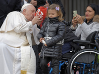 A girl holds a statuette of the Pope as Pope Francis meets with disabled attendees during the weekly general audience on November 9, 2022 at...