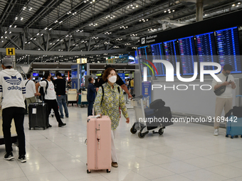 A woman seen pushes her luggage inside the departure terminal of the Suvarnabhumi International Airport on November 9, 2022 in Sumut Prakan,...