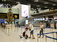 Travels seen push their luggage inside the departure terminal of the Suvarnabhumi International Airport on November 9, 2022 in Sumut Prakan,...