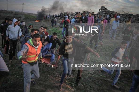 Palestinians carry a wounded Palestinian man during clashes between Palestinians and Israeli troops along the border between Gaza strip and...