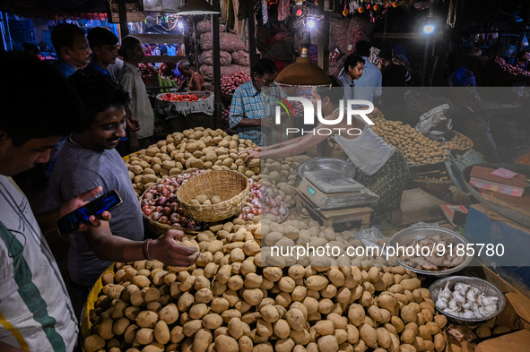 A vegetable seller sells potatoes to customers at a marketplace in Kolkata, on November 12, 2022. India's retail inflation, measured by the...