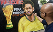 An artist works on a painting of a poster depicting soccer player Neymar ahead of FIFA Wor...