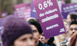 A demonstrator holds a purple sign with the feminist slogan "0.6% of rapists convicted" du...