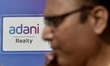 A man talks on his phone walks past an Adani logo in Mumbai, India, 23 November, 2022. Ada...
