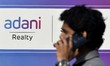 A man talks on his phone walks past an Adani logo in Mumbai, India, 23 November, 2022. Ada...
