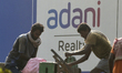 Workers are seen in front of Adani Logo in Mumbai, India, 23 November, 2022. Adani Group's...