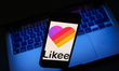 Likee logo displayed on a phone screen and a laptop are seen in this illustration photo ta...
