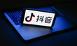 Douyin logo displayed on a phone screen and a laptop are seen in this illustration photo t...