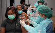 A health worker administers the COVID-19 vaccine to people at vaccination site inside the...