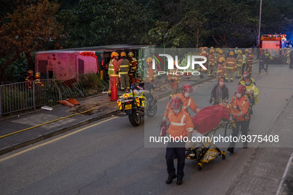 Paramedics pushing a stretcher with a patient pass a rolled over double decker bus on January 1, 2023 in Hong Kong, China. Police say 13 pas...