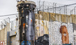 A view on a watchtower and Donald Trump street art graffiti on the Israeli separation West...