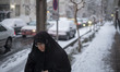 A veiled Iranian woman walks along a street-side in downtown Tehran during snowfall, Janua...