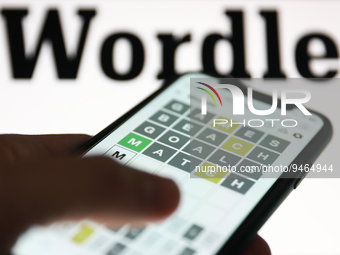 Wordle game displayed on a phone screen and Wordle logo displayed on a screen in the background are seen in this illustration photo taken in...