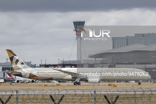 Etihad Airways Boeing 787-10 Dreamliner airplane as seen taxiing in front of the terminal building and the control tower of London Heathrow...
