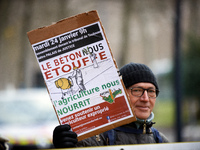 An opponent to the ZAC holds a cardboard reading 'Concrete is suffocating us, agriculture is feeding us'. Opponents to the 'ZAC du Rivel' (i...
