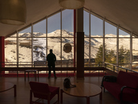 A young man observes the Alto Campoo ski resort in Cantabria (Spain) from inside the Hotel la Corza Blanca, a cozy 3-star accommodation that...