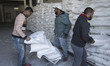 Palestinians carry bags of flour they received at UN distribution center in Shati refugee...