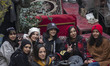 A group of young Iranian women pose for a photograph while sitting at an outdoor cafe on a...