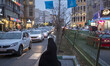 A veiled Iranian woman across an avenue in northern Tehran at sunset, January 30, 2023. Si...