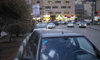 Two young Iranian women sit in a vehicle parked on a street-side in northern Tehran at sun...