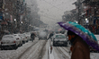 People walk as vehicles move amid heavy snowfall in Baramulla Jammu and Kashmir India on 0...