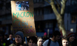 

A woman holds a cardboard sign reading ''Macron, don't play fool'' as France's labour un...