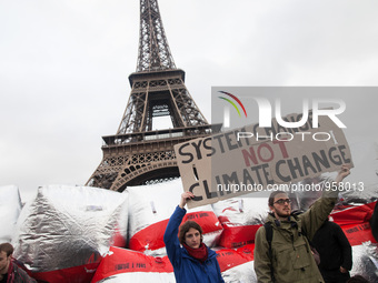 Climate demonstrators hold up a sign with the text "system change not climate change" on the bridge Pont D'iéna in front of the Eiffel Tower...