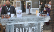 Man serves iced coffee by a bar made of solid ice at an outdoor cafe during Icefest in Tor...