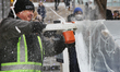 Man uses a chainsaw to carve an ice sculpture of a centaur out of blocks of solid ice duri...
