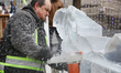 Man uses a chainsaw to carve an ice sculpture of a centaur out of blocks of solid ice duri...