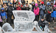 Man uses a power tool to carve an ice sculpture out of blocks of solid ice during Icefest...