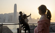A girl looking at a family taking a selfie in front of the Hong Kong Skyline on March 1, 2...