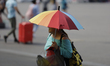 A woman protects herself from the sunlight with an umbrella in the streets of Mexico City....