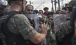 A young migrant looks through the cordon of police, where they are waiting on the Macedoni...