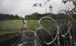 RoszRoszke,  Hungary- September 14, 2015-- Immigrants walking behind a barbed wire fence a...
