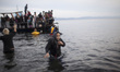 Rescuers help migrants landing on the shores of the Greek island of Lesbos after crossing...
