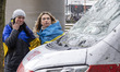 Young women from Ukraine with the Ukrainian flag around them are have an emotional reactio...