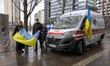 A couple from Ukraine poses with the Ukrainian flag in front of the ambulance. Ambulance h...