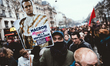 A demonstrator holds a sign depicting Emmanuel Macron dressed as the King of France distri...