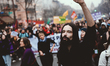 A demonstrator holds up his fist in the air in the middle of a procession of young people...