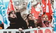 Demonstrators wave flags in the air in the middle of a procession of young people and stud...