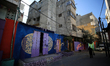 A Palestinian man walks past the facades of houses painted by artists in Gaza City, on Mar...