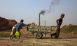 Workers are carrying raw brick in a cart to burn them in furnace. The world is going thro...