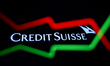 An illustrative stock chart and Credit Suisse logo displayed on a phone screen are seen in...