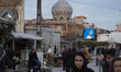 Iranian people walk along a local outdoor bazaar (Market) near a holy shrine in the city o...
