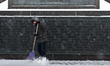 A man shovels snow at a monument in Saint Petersburg, Russia on January 4, 2016. 