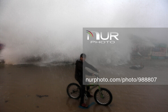 Palestinian boy pose for a photo as waves crash behind them at Gaza city's fishermen's harbor, Jan. 8, 2016 