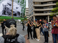 Bystanders take photos as climate change demonstrators stage a "World Bank Action Day: Ajay Banga, Get Out Of Fossil Fuels!" protest outside...