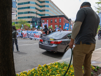 A man waters flowers as climate change demonstrators stage a "World Bank Action Day: Ajay Banga, Get Out Of Fossil Fuels!" protest outside o...